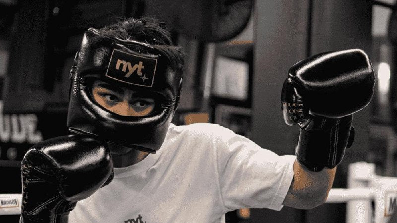Boxer in NYT boxing gloves and headgear throwing a punch